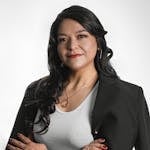 Portrait of a confident woman wearing a black blazer and white shirt, isolated on a white background.